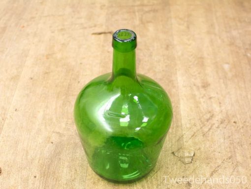 Vintage green glass bottle with embossed details on a warm wooden surface.