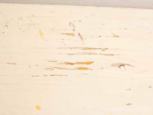 Aged white wooden table showcasing rustic charm and character through scratches and color variations.
