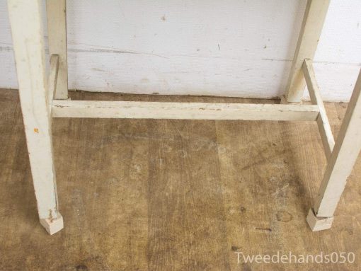 Distressed white vintage table with rustic charm and natural wood accents, ideal for country interiors.