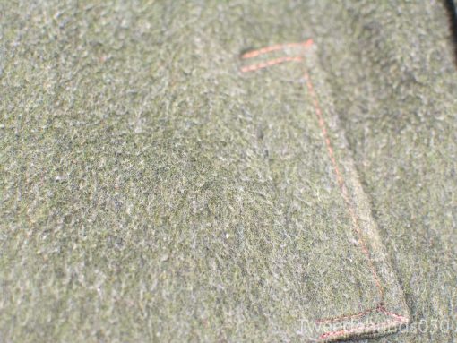 Soft green wool fabric with orange stitching, perfect for cozy, rustic fashion accessories.