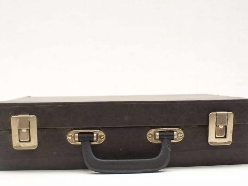 Vintage black suitcase with charm and history, perfect for travel or stylish decor.