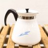 Elegant vintage white kettle with wheat design, black handle, and stainless steel rim.