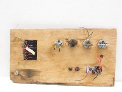 Aged wooden electronics panel with wires, switches, and knobs for creative DIY projects.
