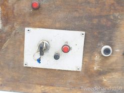 Vintage control panel on weathered wood, featuring a keyhole and emergency buttons.