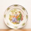 Elegant decorative plate featuring romantic scene with beautifully dressed figures from a past era.