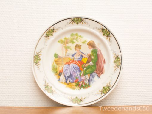 Elegant decorative plate featuring romantic scene with beautifully dressed figures from a past era.