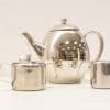 Elegant stainless steel tea set with teapot, sugar bowl, and creamer for stylish gatherings.