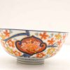 Elegant ceramic bowl with vibrant floral designs in orange, yellow, and blue glaze.
