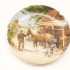 Rustic decorative plate depicting men shoeing a horse in a charming rural landscape.
