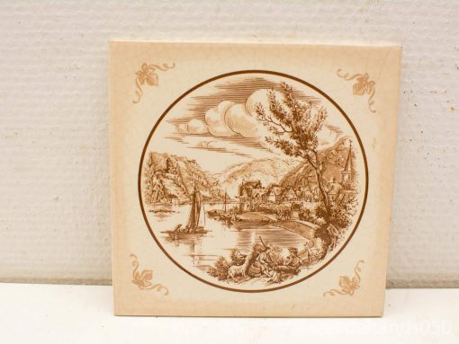 Charming vintage ceramic tile featuring a serene river landscape with sailboats and quaint homes.
