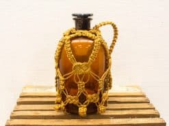 Antique amber glass jar with intricate macramé netting, perfect for decoration or storage.