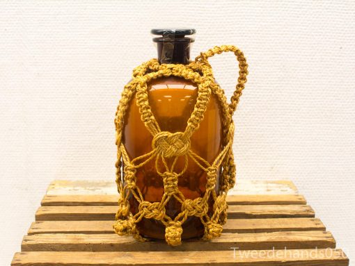 Antique amber glass jar with intricate macramé netting, perfect for decoration or storage.