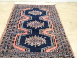 Vintage Persian rug in deep navy with coral accents and intricate hexagonal patterns.