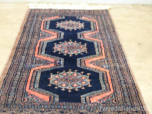 Vintage Persian rug in deep navy with coral accents and intricate hexagonal patterns.
