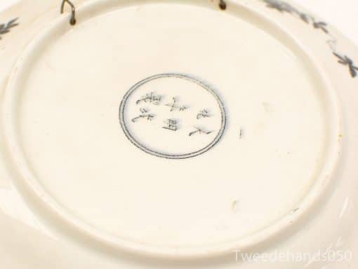 Elegant porcelain plate featuring delicate signature and intricate motifs, perfect for collectors.