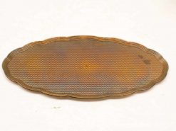 Vintage oval platter with scalloped edges and warm patina, ideal for elegant serving and decor.