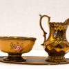 Elegant vintage set: bowl, pitcher, and tray in warm golden hues with floral details.