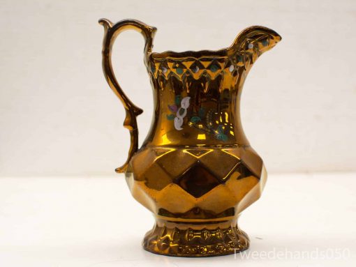 Elegant gold ceramic pitcher with floral design, perfect for decoration or serving beverages.