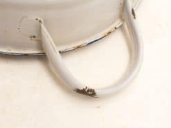 Vintage white enamel bowl with rustic charm and blue accents, perfect for decor or kitchen use.