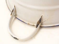 Vintage white metal container with blue rim, showing charming signs of wear and nostalgia.