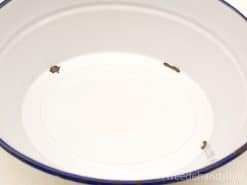 White ceramic bowl with blue trim, featuring vintage charm and subtle imperfections.