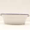 Vintage white enamel dish with blue rim and handles, perfect for serving and baking.
