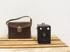 Vintage black camera and leather bag on rustic wood, perfect for photography enthusiasts.