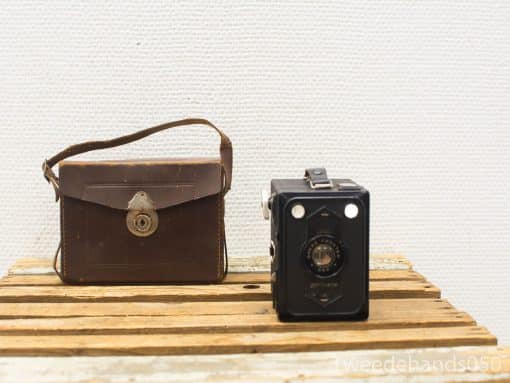 Vintage black camera and leather bag on rustic wood, perfect for photography enthusiasts.