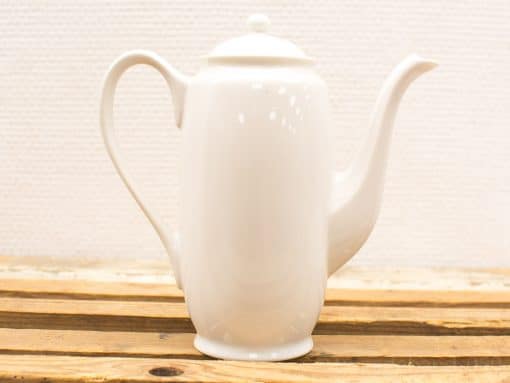 Elegant white teapot on rustic wood, perfect for refined tea ceremonies and casual gatherings.