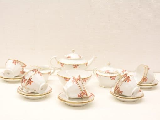 Elegant porcelain tea set with red flowers and gold trim, perfect for any occasion.