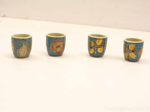 Set of 4 teal ceramic cups with vibrant botanical designs in orange and gold.