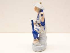 Traditional Asian porcelain figurine with intricate blue and white detailing and serene expression.