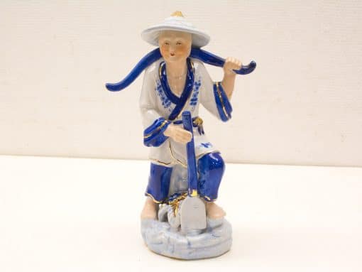 Traditional Chinese porcelain worker figurine, kneeling with shovel, celebrating agricultural heritage and craftsmanship.