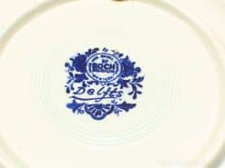 Antique Boch Delft Blue ceramic plate with intricate designs on glossy white background.