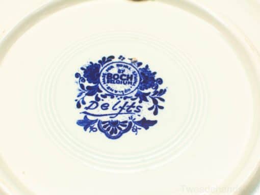 Antique Boch Delft Blue ceramic plate with intricate designs on glossy white background.