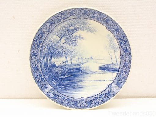Elegant blue and white porcelain plate featuring a serene nature scene and intricate detailing.