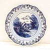 Elegant blue-and-white decorative plate featuring a charming rural house and lush landscape.