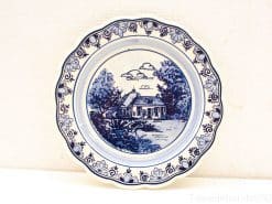 Elegant blue-and-white decorative plate featuring a charming rural house and lush landscape.