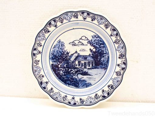 Elegant blue-and-white decorative plate featuring a charming rural house and lush landscape.