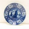 Blue and white ceramic plate featuring sailboats and floral border, perfect for display or serving.