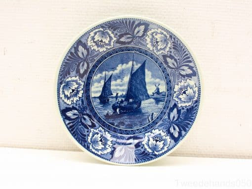 Blue and white ceramic plate featuring sailboats and floral border, perfect for display or serving.
