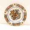Elegant decorative plate featuring vibrant floral designs in warm colors on a white background.