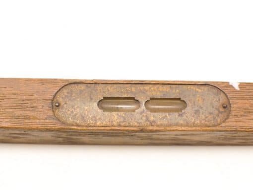 Vintage wooden level with glass vials and aged metal backing, showcasing craftsmanship and history.
