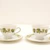 Elegant porcelain teacups with ivy pattern and gold trim, perfect for sophisticated tea gatherings.