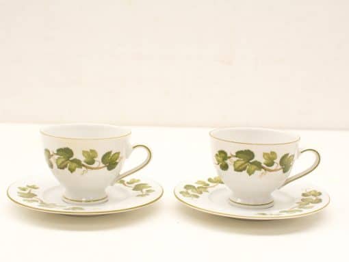 Elegant porcelain teacups with ivy pattern and gold trim, perfect for sophisticated tea gatherings.