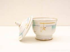 Elegant vintage porcelain container with lid, adorned with pastel colors and golden accents.