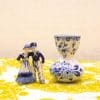 Charming Delft blue couple and vase set against vibrant yellow backdrop for stylish decor.