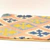 Vibrant geometric cushion with peach background and rich blue, yellow, and cream patterns.