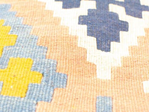 Vibrant vintage cushion cover with geometric patterns in pink, blue, and yellow hues.