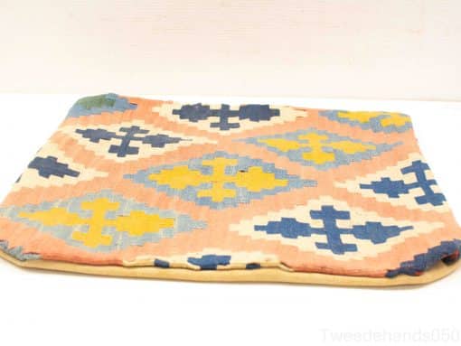 Vibrant geometric cushion with peach background and rich blue, yellow, and cream patterns.